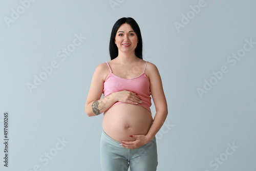 Pregnant young woman on grey background