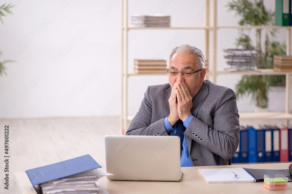 Old male employee working at workplace Old male employee working at workplace