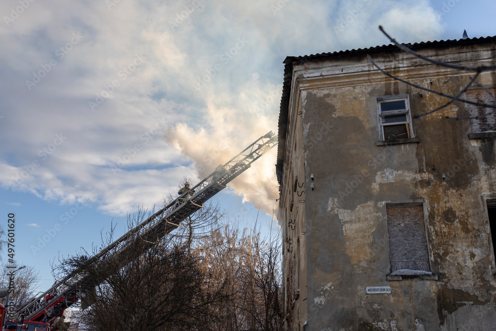 Firefighter works on boom of fire engine. Fireman on sky background. Burning old building in the historic center..Rescuers on a retractable ladder in the smoke. Firefighter works on boom of fire engine. Fireman on sky background. Burning old building in the historic center..Rescuers on a retractable ladder in the smoke.