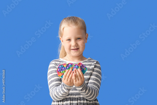 Portrait of little girl with different pop it fidget toys on color background