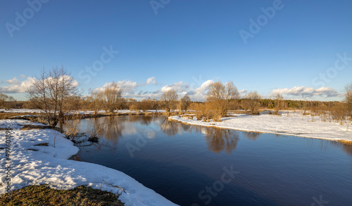 March sunny day by the river. A picturesque landscape  early spring  a river with snow-covered banks. The first thaws  the snow is melting.