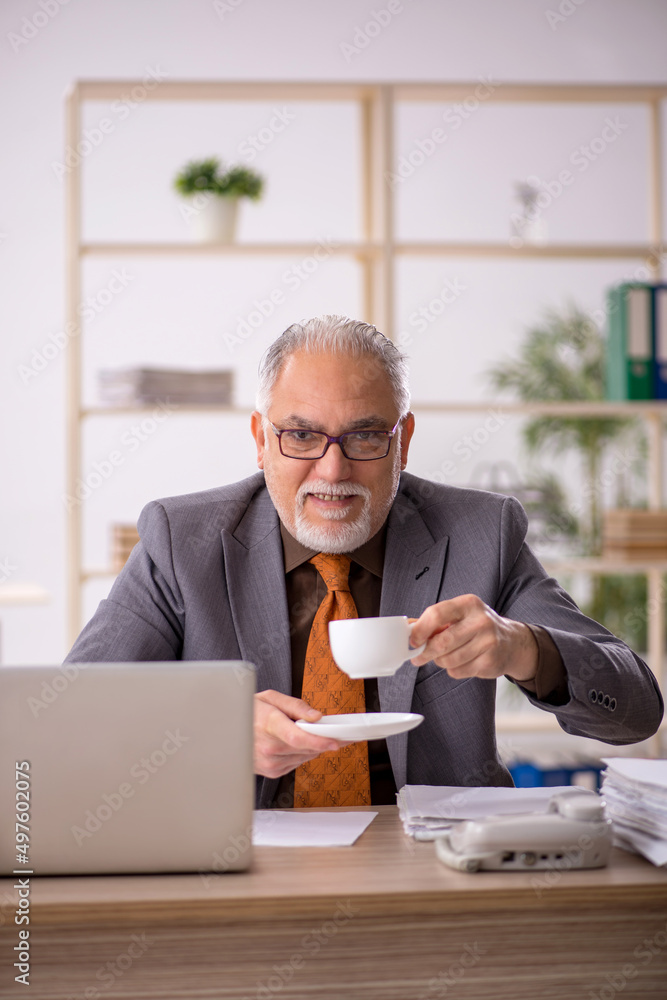 Old male employee drinking coffee during break Old male employee drinking coffee during break