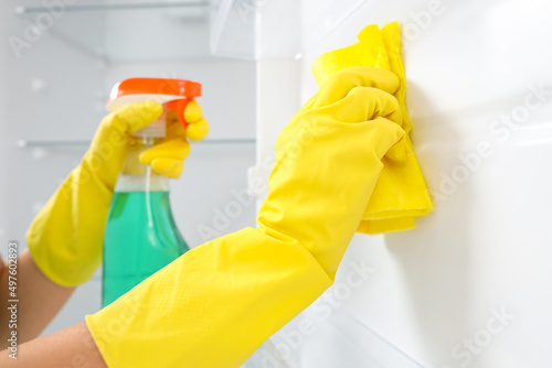 Young woman cleaning refrigerator in kitchen, closeup