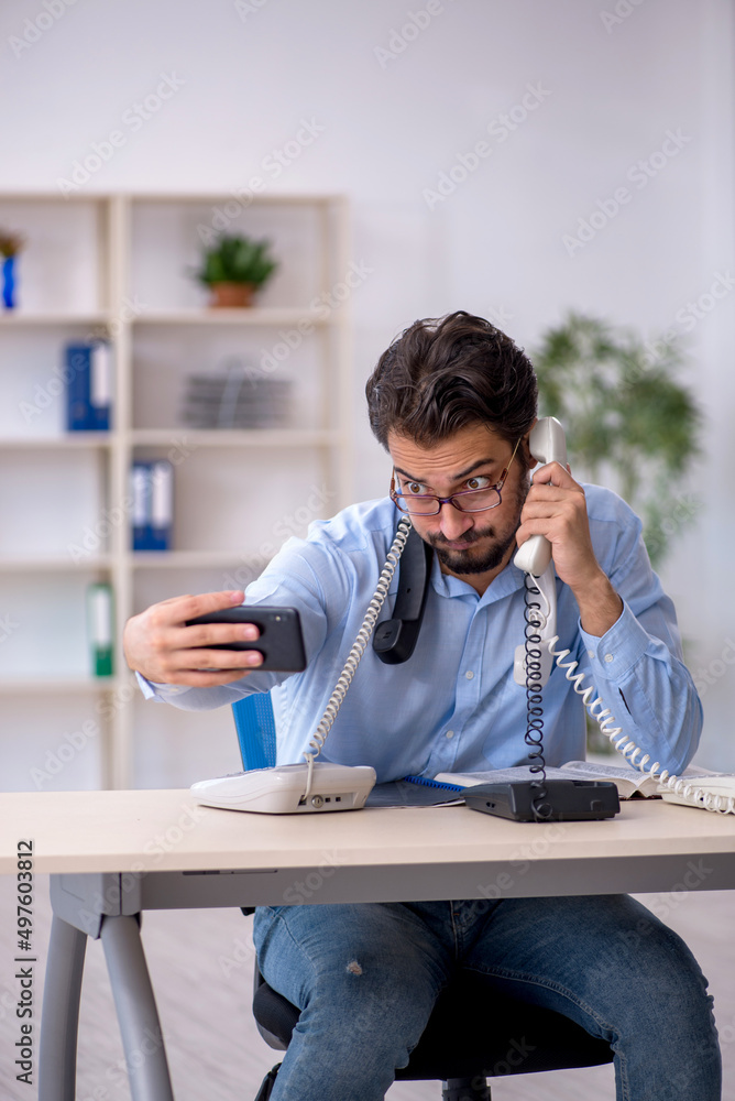Young male call center operator working at his desk Young male call center operator working at his desk