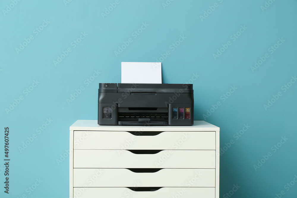 Modern printer on chest of drawers near blue wall Modern printer on chest of drawers near blue wall