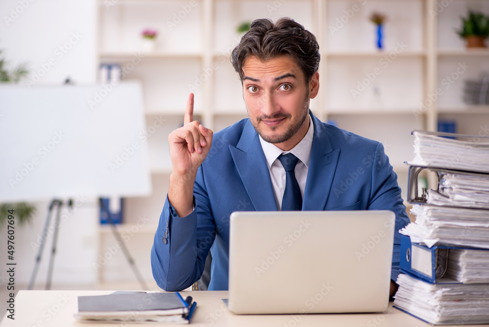 Young male employee and too much work in the office Young male employee and too much work in the office