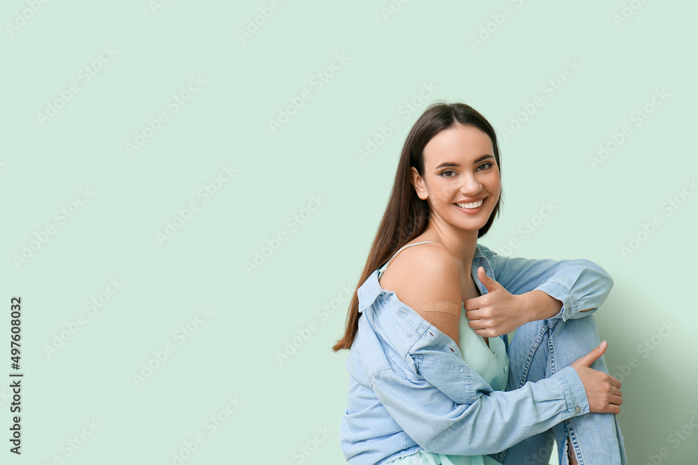 Obraz premium Young woman with applied medical patch showing thumb-up on color background