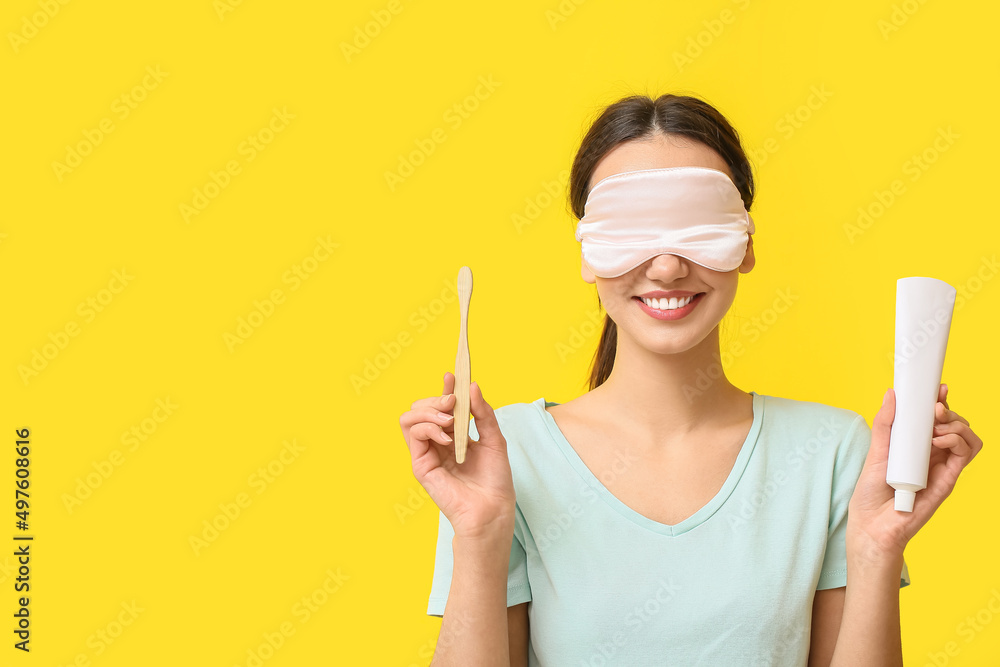 Smiling young woman in sleeping mask with tooth brush and paste on yellow background Smiling young woman in sleeping mask with tooth brush and paste on yellow background
