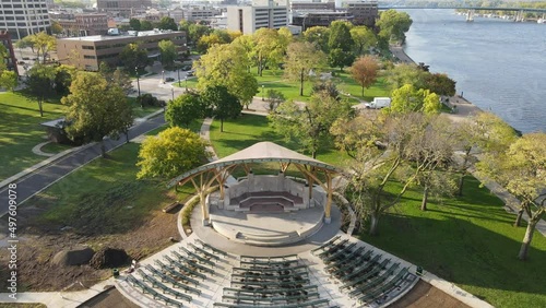 Close up then pan out over bandshell renovations in Riverside Park along the Mississippi River in Wisconsin. Constuction near complete of concrete. Downtown area in the distance. Big blue bridge.