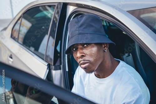 Portrait of a black man sitting in a car with an open door.