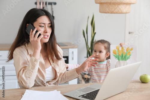 Canvas Print Little daughter keeping mother from her work at home