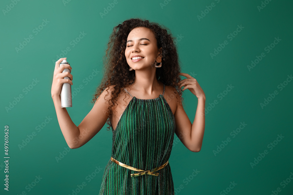 Pretty young African-American woman with hair spray on green background Pretty young African-American woman with hair spray on green background