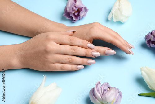 Female hands with beautiful manicure and tulips on blue background, closeup
