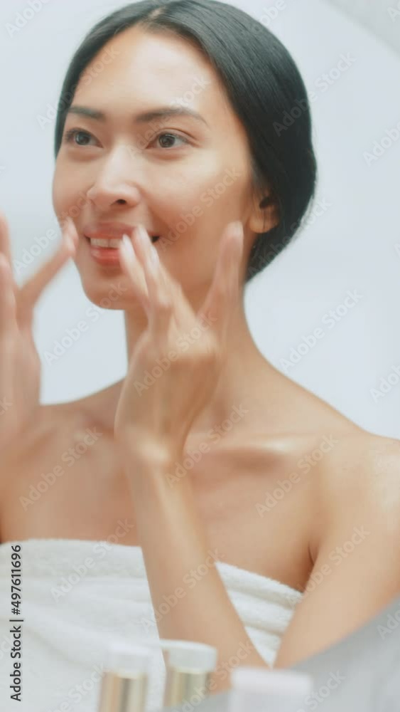 Vertical Screen. Beautiful Asian Woman Her Perfect Soft Face Skin, Uses Advanced Organic Cream, Smiles in the Mirror. Happy Female Enjoying Her Morning Routine. Natural Beauty, Cosmetic Products Vertical Screen. Beautiful Asian Woman Her Perfect Soft Face Skin, Uses Advanced Organic Cream, Smiles in the Mirror. Happy Female Enjoying Her Morning Routine. Natural Beauty, Cosmetic Products