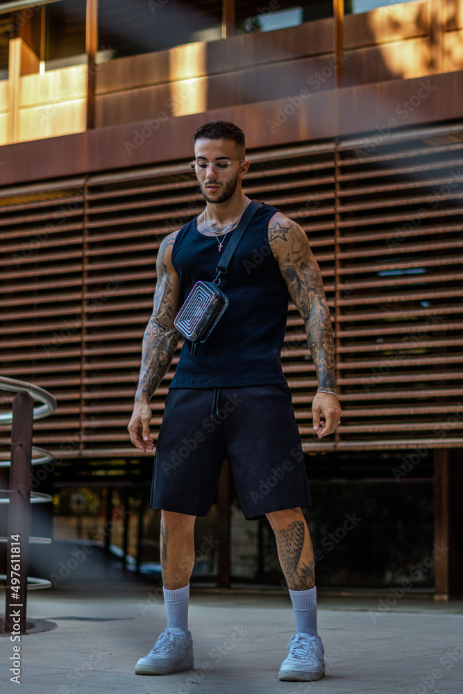 Caucasian sporty male with tattoos standing in the street