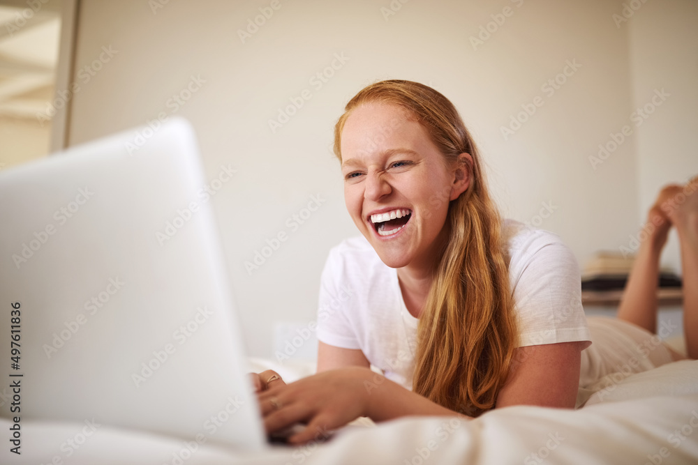 The internet always has something that will make you laugh. Shot of a young woman laying in bed at home. The internet always has something that will make you laugh. Shot of a young woman laying in bed at home.