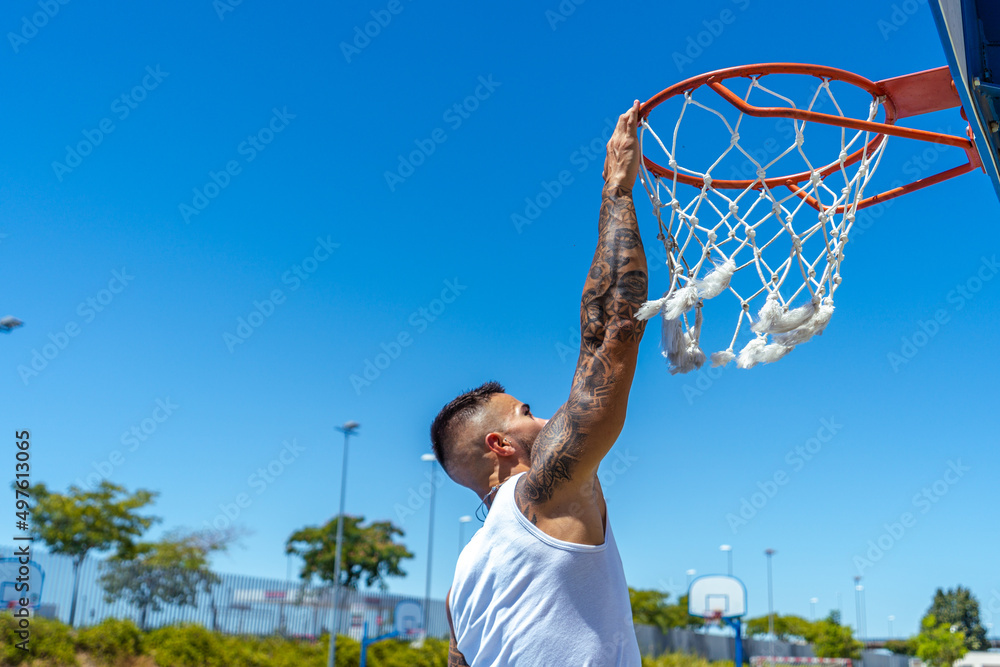 Sporty Caucasian male with tattoos playing basketball