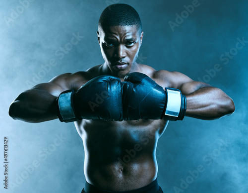 I dont hate, I dominate. Studio shot of a handsome young man boxing against a blue background.