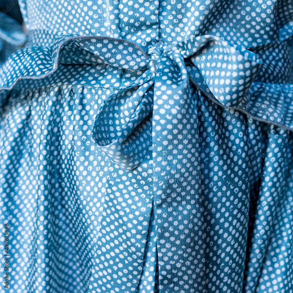 Fragment of a woman's blue polka dot dress. The belt is tied to a bow. High quality photo Fragment of a woman's blue polka dot dress. The belt is tied to a bow. High quality photo
