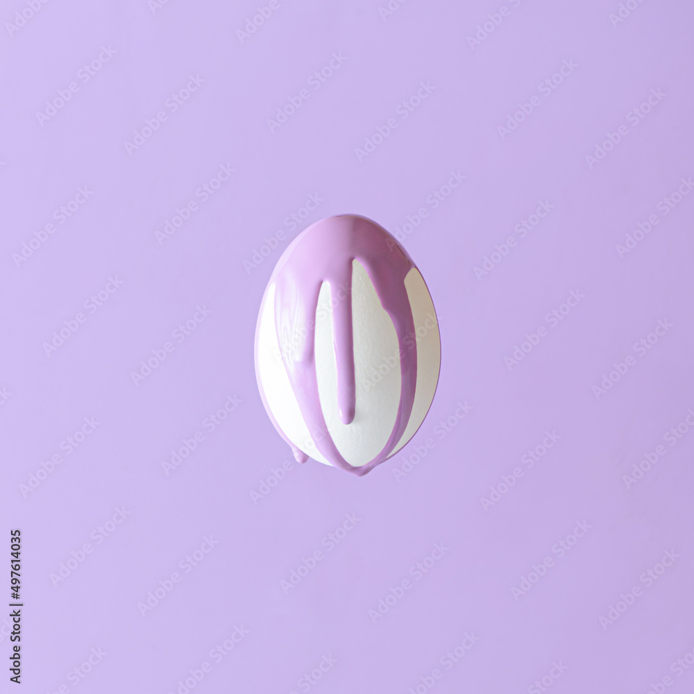 Obraz premium A white Easter egg on a pastel purple background from which purple paint is dripping. Easter egg aesthetic monochrome concept.