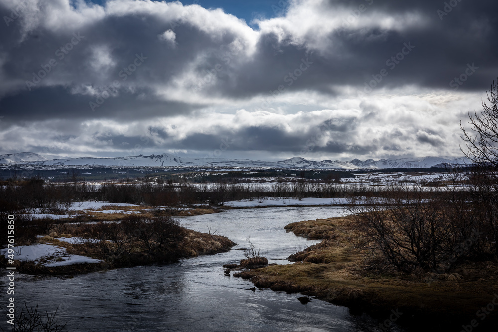 A lake in suburbs of Reykjavik, Iceland. Snowy mountain range in background, cloudy sky. 