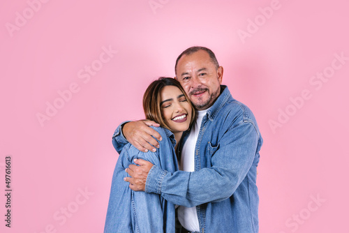latin father and daughter in casual clothes in a copy space on pink background in Mexico Latin America	
