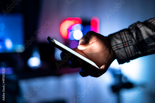Fototapeta person holding smartphone and scrolling on web page at night