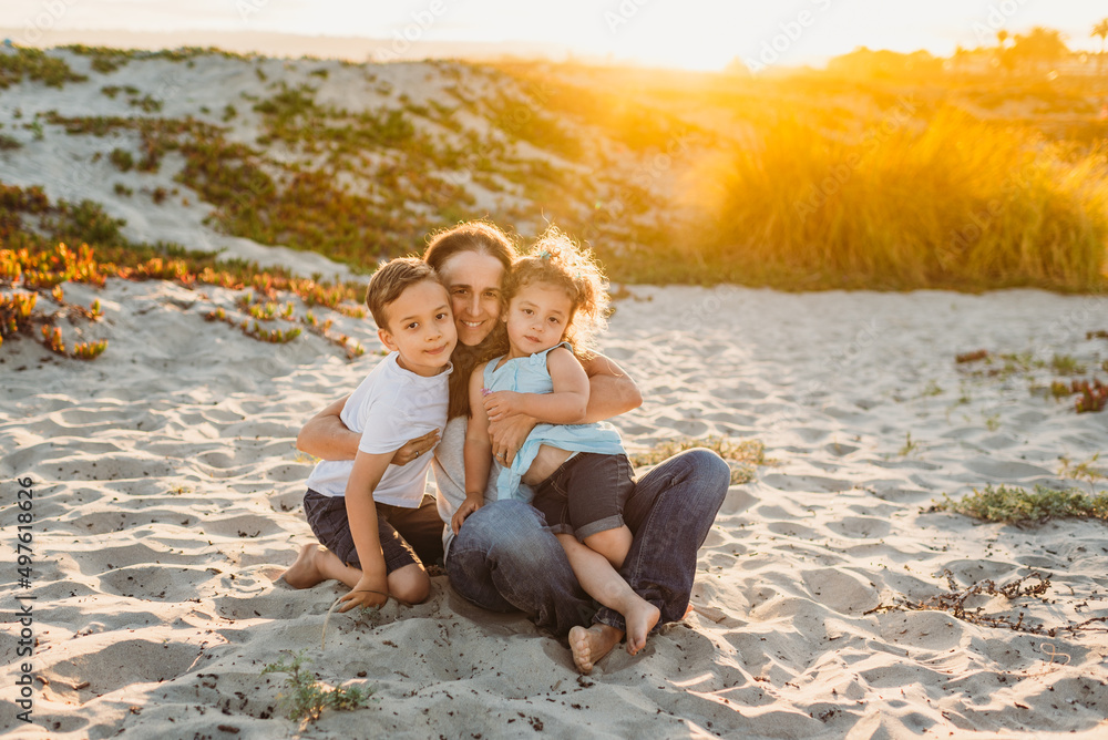 Happy mom sitting in sand with children Happy mom sitting in sand with children