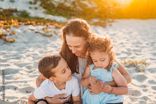 Mother sitting in sand with young children