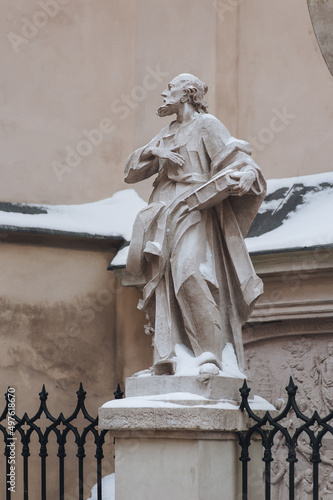 A snow-covered sculpture of a supposedly Christian apostle holding a book stands near the Latin Cathedral in Lviv, Ukraine. photo