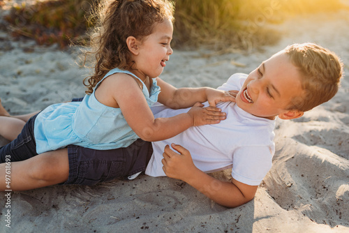 Laughing siblings playing in the sand photo