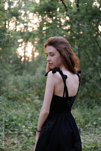 attractive young brunette woman in a black dress posing in the forest. freedom. fashion portrait