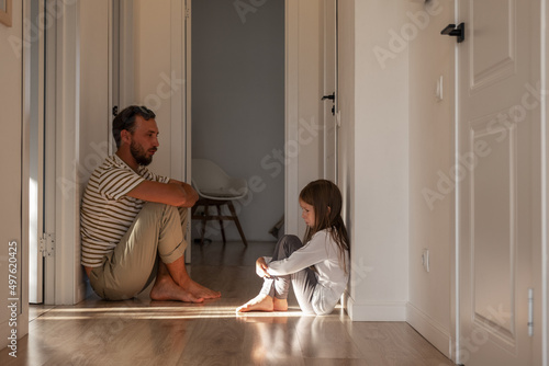 Upset daughter sitting in corridor with father photo