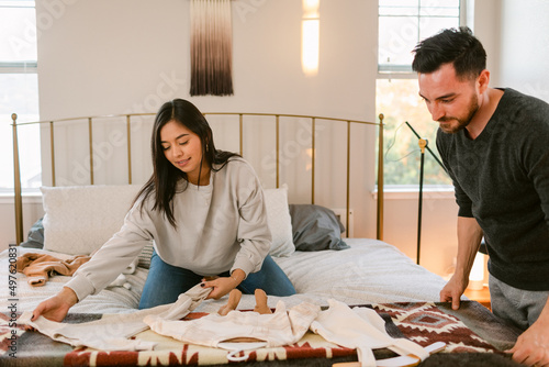 Couple watching baby clothes in bedroom photo