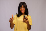 beautiful young black woman using her phone looking amazed and did thumbs up