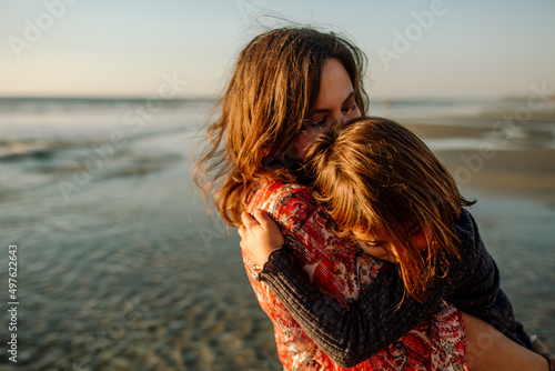 Mother soothing daughter on beach photo