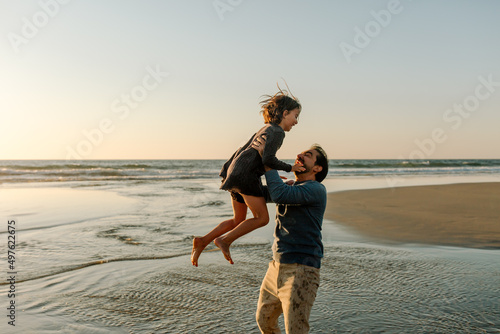 Father lifting daughter into the air at the beach