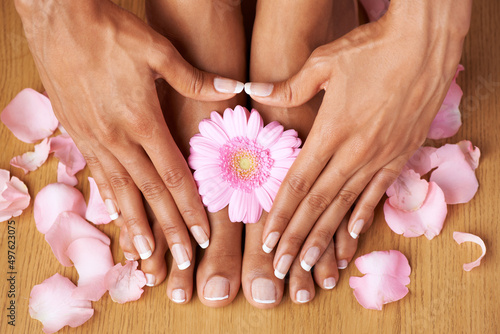 Floral beauty. Cropped view of hands on perfectly pedicured feet with flowers all around.