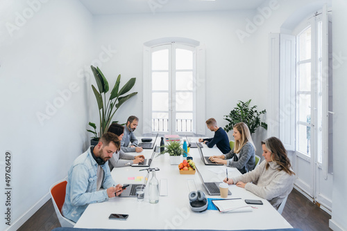 Group of colleagues working on laptops in boardroom photo