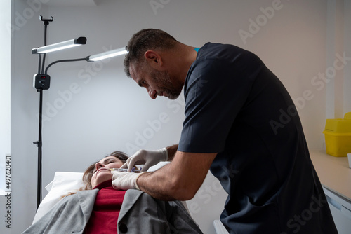 Male beautician making a lips injection to client