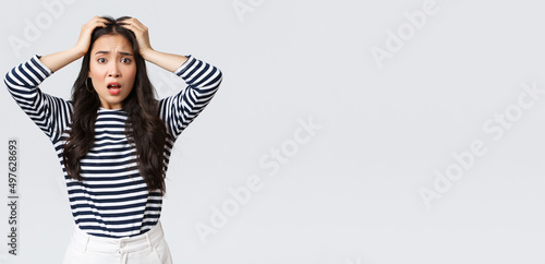 Lifestyle, people emotions and casual concept. Troubled young woman stare alarmed, feel bad as something awful happened, grab head and stare camera anxious, white background photo
