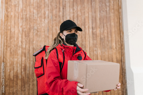 Woman in mask delivering carton box to addressee photo