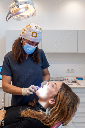 Female dentist examining gums and teeth of female client photo