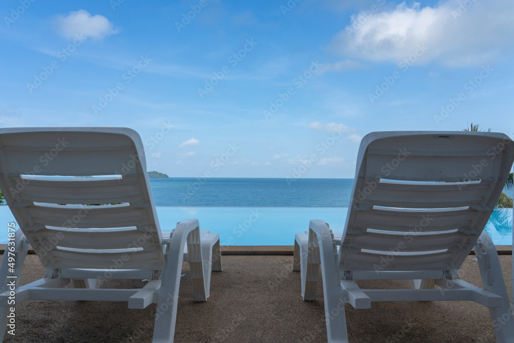 Two sun loungers stand by the pool against the blue sky.