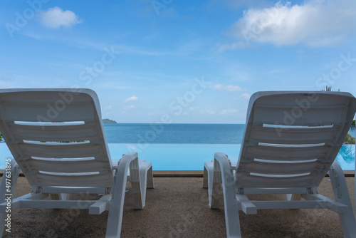 Two sun loungers stand by the pool against the blue sky.