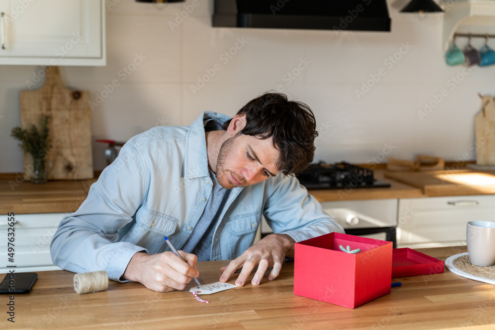 Man writing gift card in modern kitchen Man writing gift card in modern kitchen