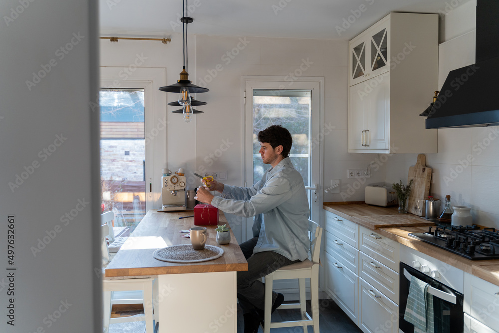 Man wrapping give away in modern kitchen Man wrapping give away in modern kitchen