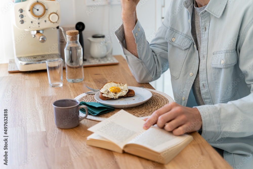 closeup of man having breakfast and reading book closeup of man having breakfast and reading book