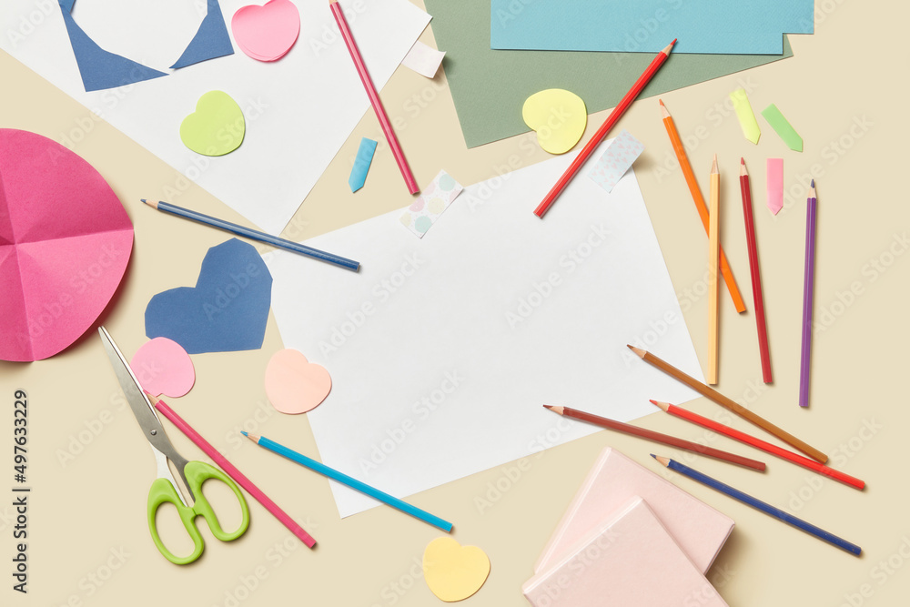 Beige background with pencils, paper sheets and scissors Beige background with pencils, paper sheets and scissors