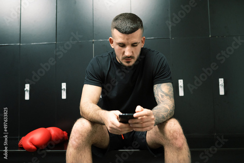Boxer with smartphone sending text message in dressing room befo photo